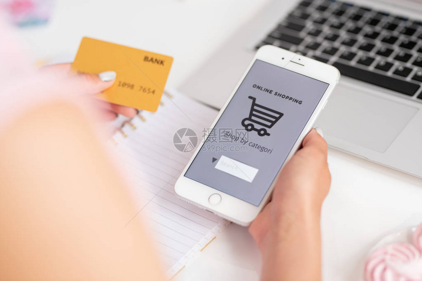 网上商店的年轻消费者用智能手机和银行卡在网上搜索商品图片