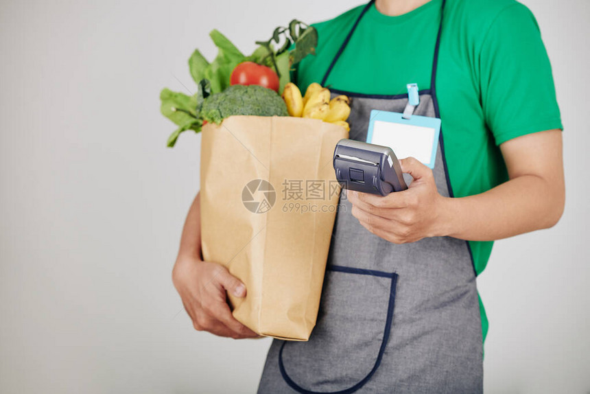 超市工人携带新鲜杂货和付款终端的全套新食品和付款图片