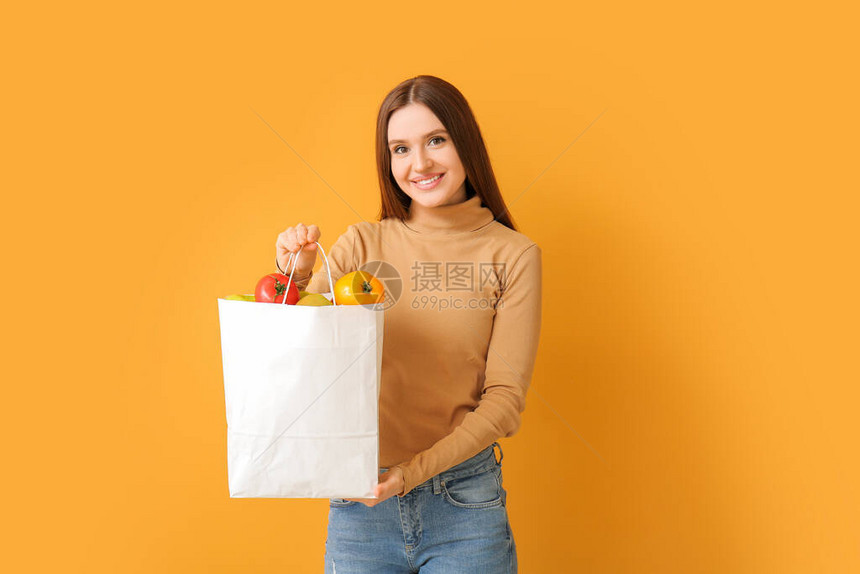 青年妇女拿着包袋带着有彩色食物的图片