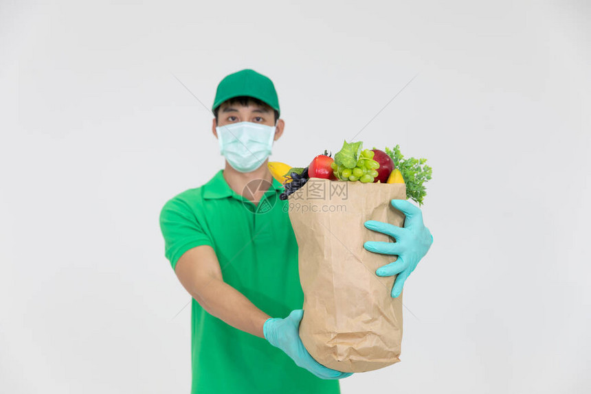 身穿绿色制服头戴面罩的智能送餐人员将新鲜食物递给收件人图片