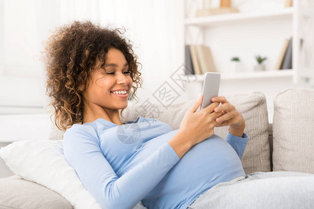 快乐的孕妇在智能手机上网图片