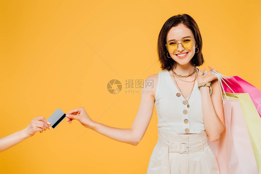 戴墨镜的快乐女孩带着购物袋拿着信用卡在图片