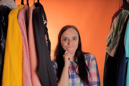站在衣橱里的衣服之间做鬼脸的年轻女人成年女在商图片