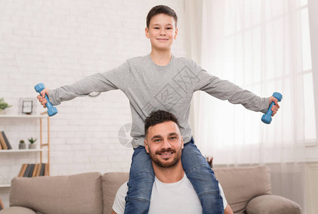 在隔离期间的体育训练快乐的父亲和儿子在家用哑铃运图片