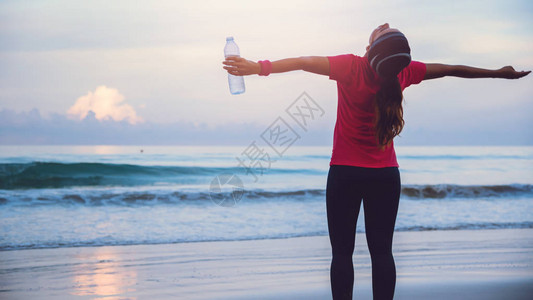 请您喝水您可以在海边散步和用塑料瓶喝水来放松身心背景
