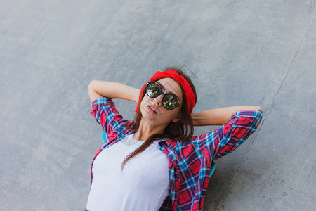 戴着时装镜像眼镜的年轻时尚女孩红格子衬衫和绷带在她头上躺在滑冰场图片