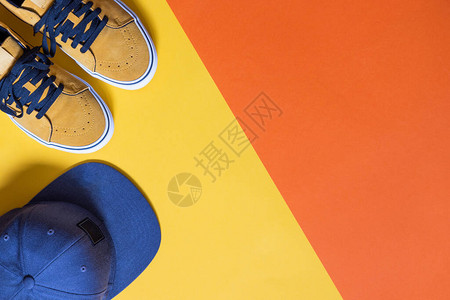 横向模型双颜色黄和橙色背景的芥末彩色鞋子以及蓝色帽图片