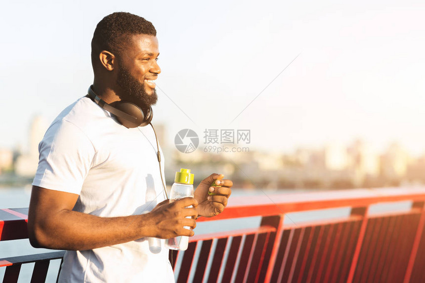 手持水瓶的非洲男子微笑坐在桥上阳光明图片