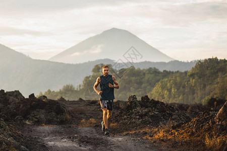 年轻的员男子早上在山上跑步背景中巴厘岛阿贡山令人惊叹的火山景观健康的图片