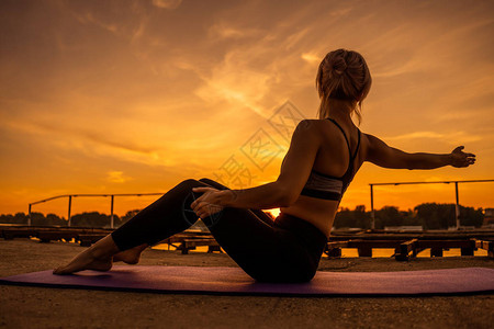 日落时锻炼普拉提的女人图片