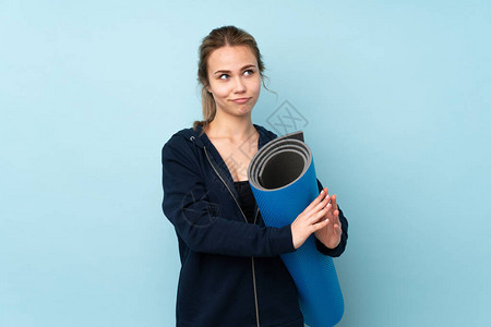 年轻俄罗斯女孩拿着垫子孤立在蓝背景下图片