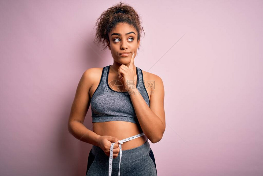 年轻非裔美国体育女运动员在腰部严肃的脸上用胶带测量器控制体重图片