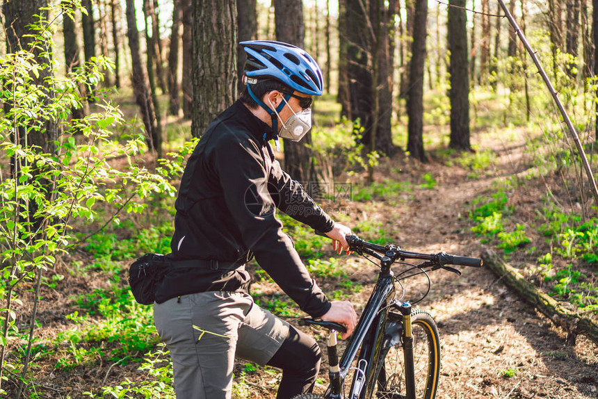 年轻人在森林里骑山地自行车年轻健壮的男人在公园里骑自行车男骑自行车者戴着面部呼吸器图片