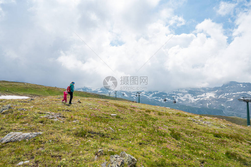 母亲和女儿徒步到绿色高山牧场图片