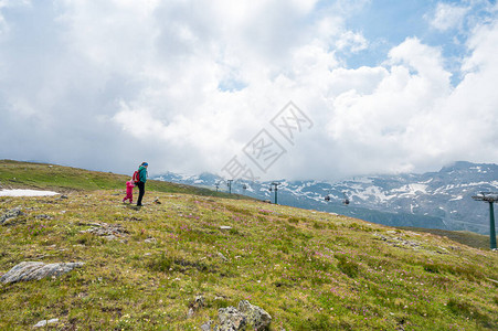 母亲和女儿徒步到绿色高山牧场图片