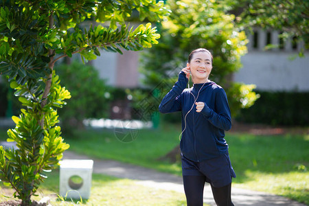 亚洲女人在乡村公园跑步和听音乐的画像快乐的跑步者在公园图片