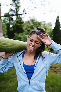 年轻快乐的女运动家拿着健身地毯在城市图片