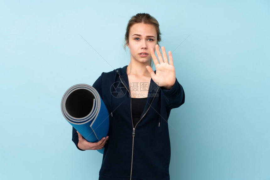 俄罗斯女孩拿着被孤立在蓝背景神经紧张的垫子手伸图片