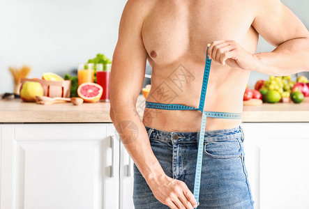 健壮的肌肉人厨房里有测量胶带图片