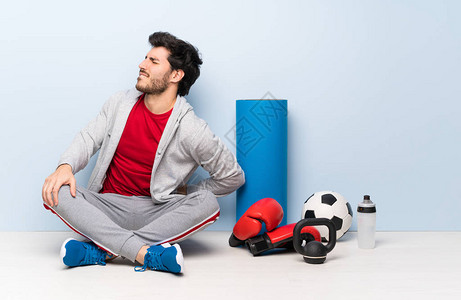 坐在地板上的运动男子因努力而患有背痛症图片