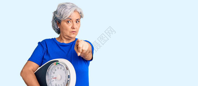 头发灰白的高级女拿着举重机来平衡体重减轻图片