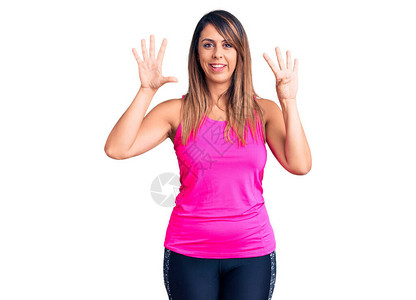 身穿运动服的年轻美女带着九号指着手指满怀自信和快乐图片