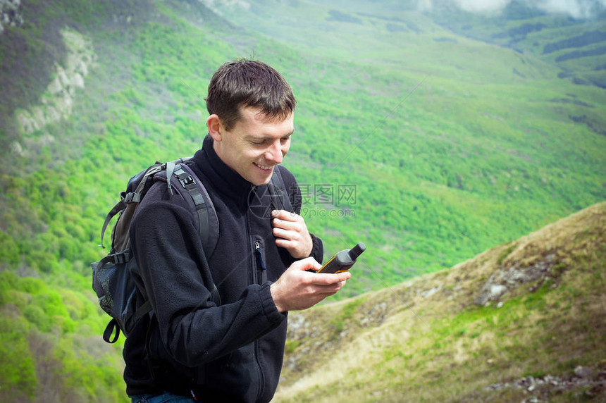 手持GPS导航器全球定位系统设备的年轻男子游客的画像山夏天图片