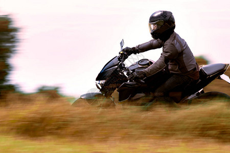 骑运动摩托车的人靠在曲线路上图片