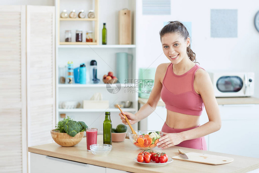 腰部上画出健康年轻女在厨房内烹饪健身食品对着镜头微笑复图片