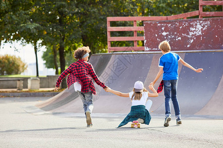两个男孩在户外滑板公园玩耍时一起骑着女孩玩图片
