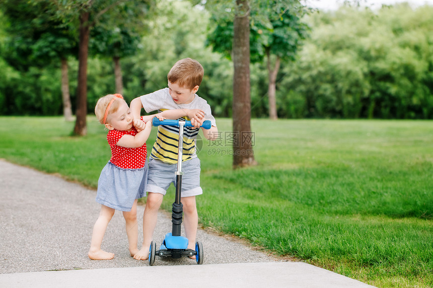 两个小高加索学龄前儿童互相打架男孩和女孩不能共用一辆滑板车哥不把玩具给妹图片