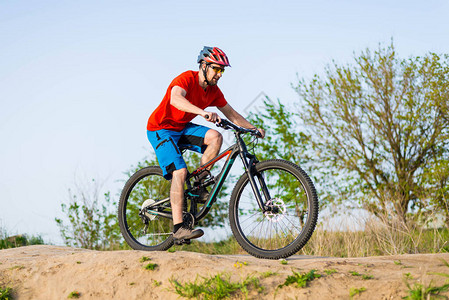 一名身穿橙色T恤和头盔的自行车手骑着山地自行车极限自行车图片