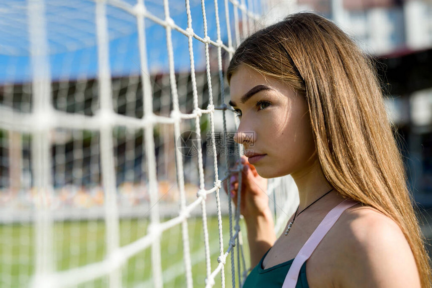 一个身材完美的漂亮女孩站在体育场的足球门附近健身和健康的图片