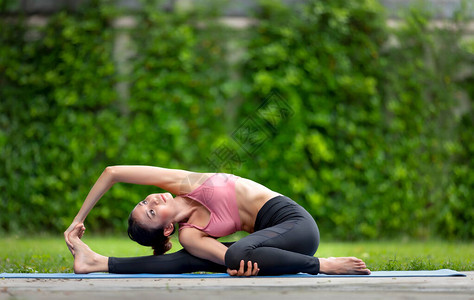 令人惊叹的亚洲年轻健身女子在花园户外做瑜伽伸展练习图片