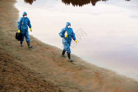 年轻女研究人员带着脏水和泥土沿着河边移动图片
