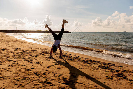 剪影女人翻筋斗和海滩日落锻炼运动和健康的生活方式新的一天图片