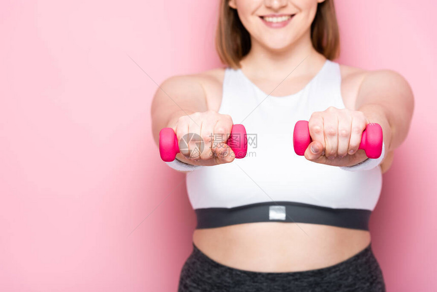 微笑的超重女孩用粉色哑铃锻炼的剪影图片