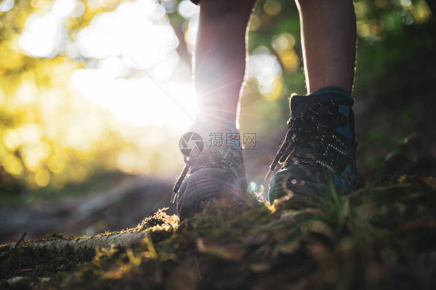 低角度的视野一个孩子腿在徒步靴中站在山丘小径上被发光图片