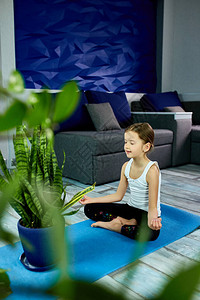 一个女孩坐在蓝色背景上的瑜伽体式中图片