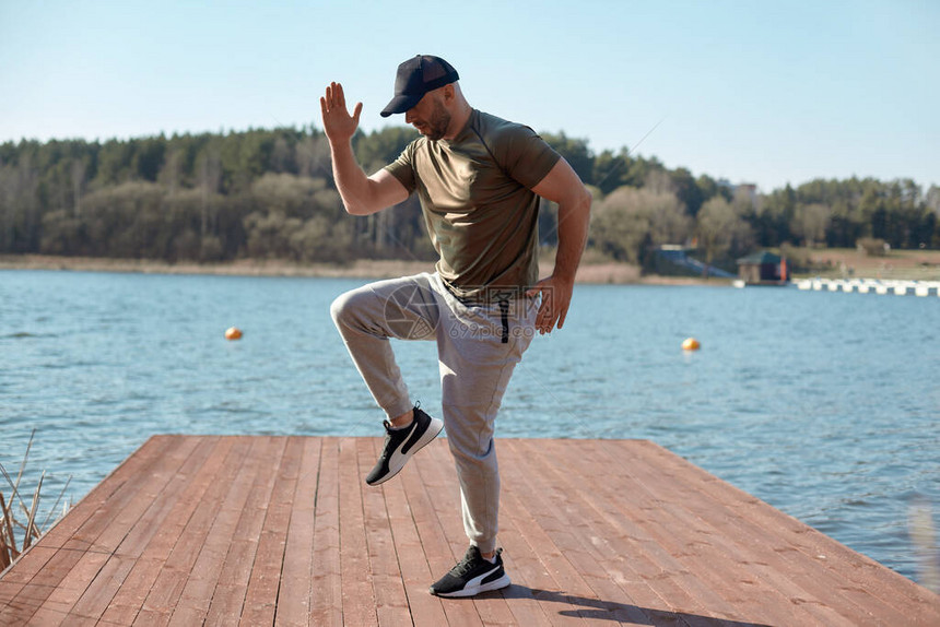 一个穿着运动服的健壮的男人在湖边的码头上做运动一个男人做运动运动健图片