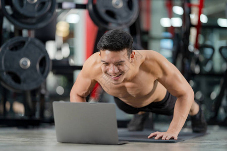 在线训练运动男子训练在健身房用笔记本电脑图片