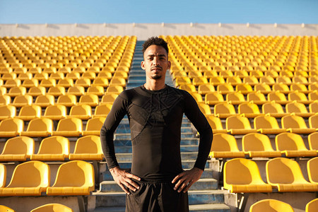 年轻英俊的非裔美国运动员满怀自信地在空体育场座椅图片