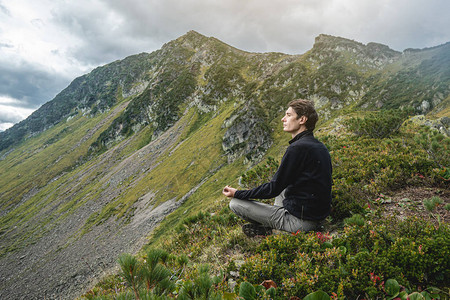 坐在夏天山峰顶的瑜伽姿势上的人图片