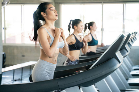 在健身房的跑步机上跑步的亚洲运动女群体图片
