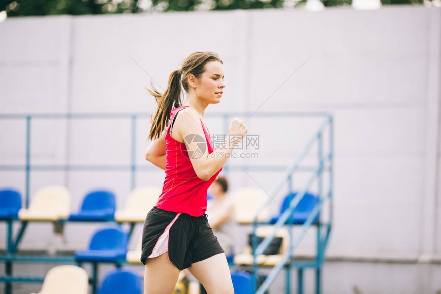 跑在体育场的妇女在体育场跑道上跑步的年轻女子目标成就概念在球场上进行健身慢跑锻炼健康主题成功的运动图片