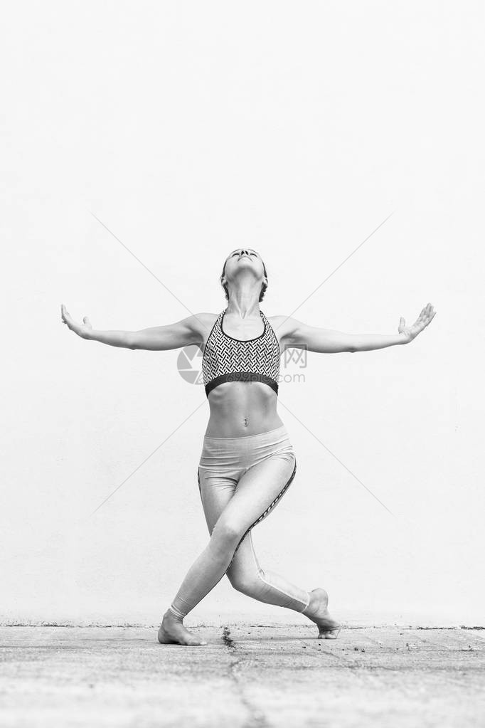 适合运动活跃的女孩穿着时尚运动服在灰墙前做瑜伽健身运动户外运动都市风图片