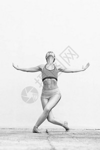 适合运动活跃的女孩穿着时尚运动服在灰墙前做瑜伽健身运动户外运动都市风图片