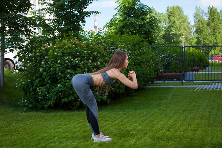 一位身穿运动型短上衣和健身紧裤的黑发女教练展示了正确的向前倾斜技术图片