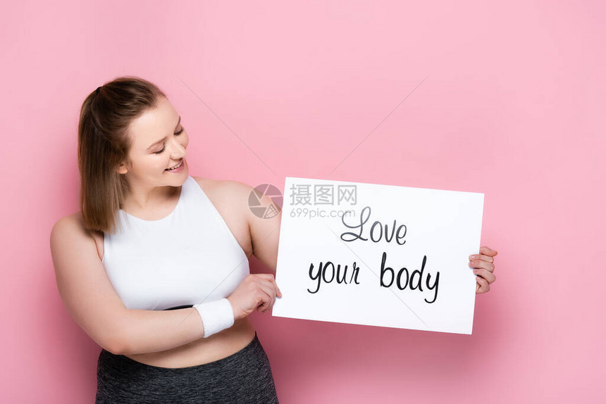 快乐的超重女孩拿着标语牌爱着你的身体在图片