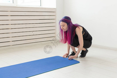 有彩色发型折叠体操运动垫和体育课后在健身房里放课的年轻瘦图片